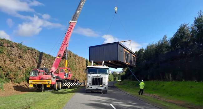 House being lifted off of a truck into position by crane