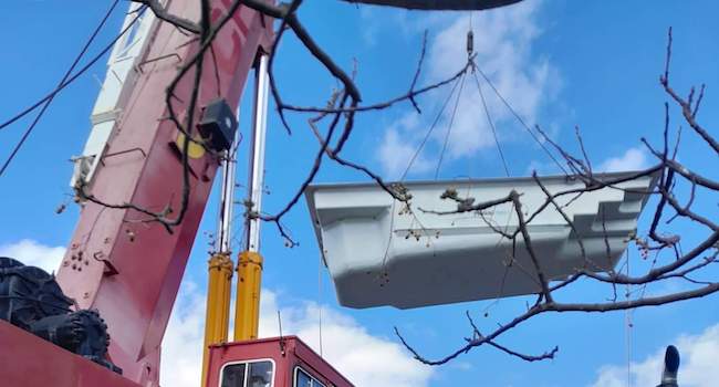 Pool liner being lifted over a house by crane